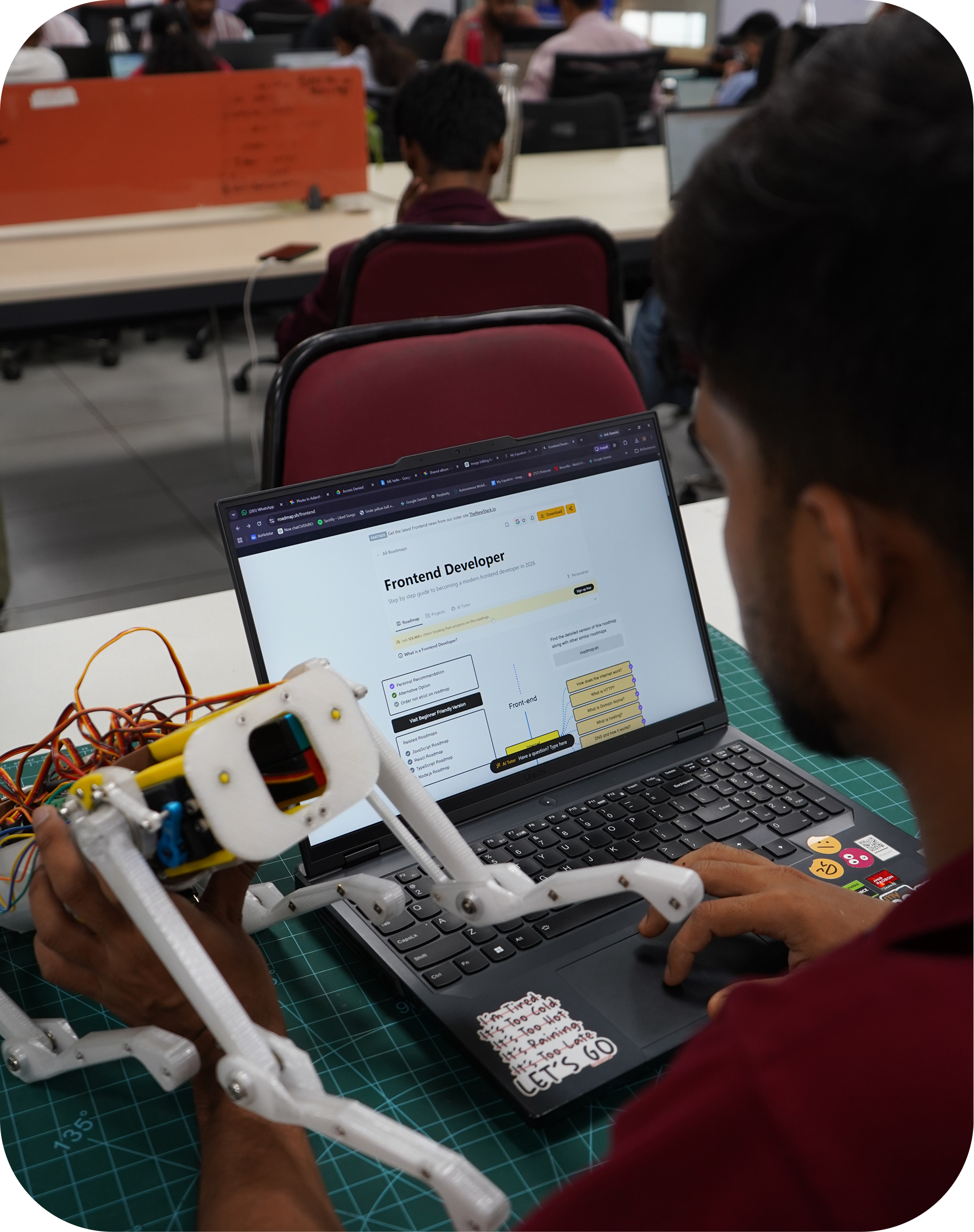 Student working hands-on with a robotic arm alongside a laptop