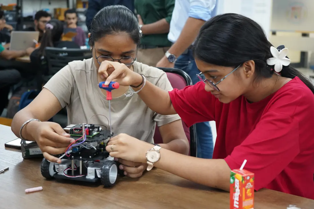 Two learners assembling a wheeled robot at a workbench